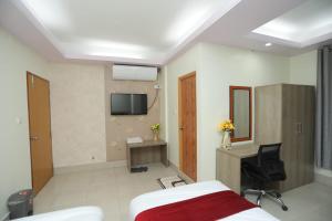 a room with a bed and a desk and a tv at Wood Burn Hotel in Bogra