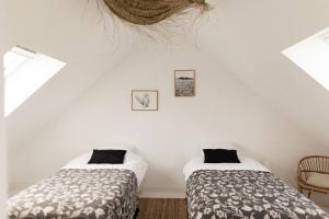 two beds in a room with two windows at Men Louet O - Gîte de bord de mer in Ploudalmézeau