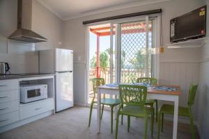 een keuken met een tafel en stoelen en een keuken met een balkon bij Peoples Park in Coral Bay