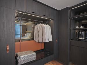 新加坡Pullman Singapore Hill Street的一个房间里有一个衣柜，里面有白色的衣服和一面镜子