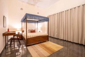 1 dormitorio con cama con dosel y escritorio en StayVista at Villa Gardenia The Garden Villa - Aurai en Gyānpur