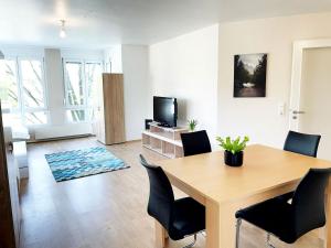 sala de estar con mesa, sillas y TV en Workers Apartment in Offenbach, en Gravenbruch