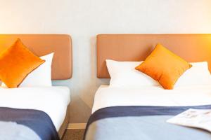 大阪市にあるApartment Hotel 11 Umedaのオレンジの枕が備わるホテルルームのベッド2台