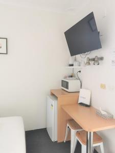 een bureau met een computer en een tv aan de muur bij Bathurst Explorers Motel in Bathurst