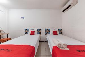 two beds in a room with red and white sheets at RedDoorz Syariah At Cibadak Sukabumi in Sukabumi