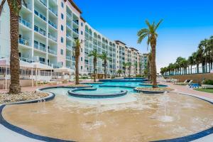 einem Pool mit Palmen vor einem Gebäude in der Unterkunft Diamond Beach Resort Sunshine Sea Breezes in Galveston