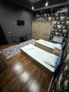 1 dormitorio con 2 camas y TV. en TURKISTAN Hotel en Kogon