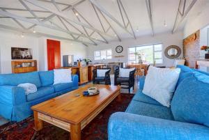ein Wohnzimmer mit blauen Sofas und einem Holztisch in der Unterkunft Jolie Beach Apartment in Wilderness