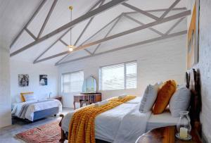 ein Schlafzimmer mit einem großen Bett mit weißer Bettwäsche und orangefarbenen Kissen in der Unterkunft Jolie Beach Apartment in Wilderness