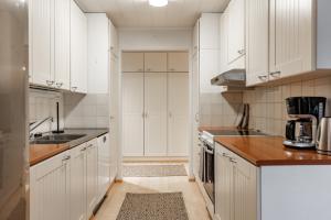 a white kitchen with white cabinets and a sink at Arctic Holiday Apartments 2 in Rovaniemi