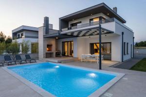 eine Villa mit einem Swimmingpool vor einem Haus in der Unterkunft Villa Marita 2 in Privlaka