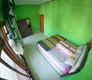 - une vue sur la hauteur sous plafond d'une chambre verte avec 2 lits dans l'établissement Grand Berbah Homestay Jogja, à Potrojayan
