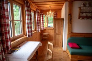 a room with a table and a couch and windows at Haus Seegarten in Grundlsee