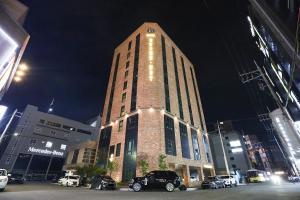 a tall brick building with cars parked in a parking lot at Brown Dot Hotel Ulsan Samsan in Ulsan