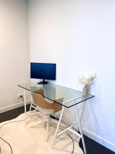 a glass desk with a computer monitor and a chair at Anthem Stylish 1BR Apartment - with top amenities and easy airport access in Melbourne