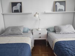 1 dormitorio con 2 camas y mesita de noche con lámpara en Dúplex en Parque Europa, en Ezcaray