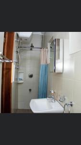 La salle de bains est pourvue d'un lavabo et d'un rideau de douche bleu. dans l'établissement Luxor garden apartments, à Accra