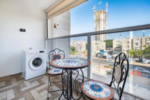 uma varanda com uma mesa e cadeiras e uma máquina de lavar roupa em יחידת דיור ברמת בית מלון עם ממד em Ashdod