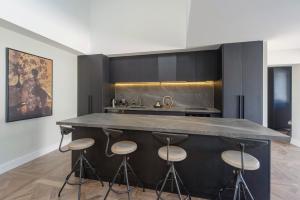 cocina con encimera grande con taburetes en Monaco Poolside Apartment, en Nelson