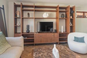 una sala de estar con TV en un centro de entretenimiento de madera en Monaco Poolside Apartment, en Nelson
