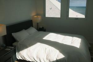 a bedroom with a large white bed with two windows at Aloha Beachfront ホノルル - Hawaii Kai in Honolulu