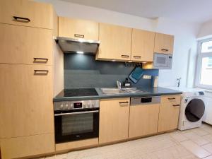 a kitchen with wooden cabinets and a stove and a sink at Viel Platz für Gruppen inkl. Waschmaschine, Hochstuhl und Playstation mitten in der Altstadt in Amberg