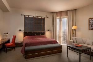 una camera da letto con un letto, un divano e un tavolo di Tufenkian Historic Yerevan Hotel a Yerevan