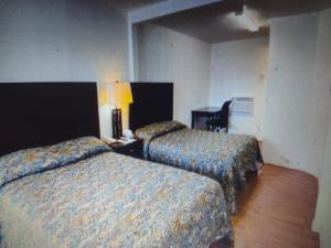 una habitación de hotel con 2 camas y una silla en Budget Inn & Suites Lowest Price Daily & Weekly, en Freer