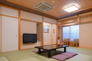 Una sala de estar con una mesa y un televisor. en Yuno Yado Shoei, en Kioto