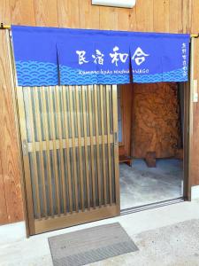 Una puerta a un edificio con un cartel. en 民宿 和合 Minshuku WAGO en Tanabe