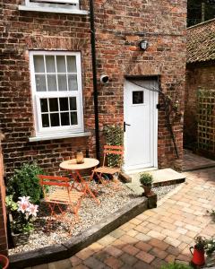un patio con tavolo e 2 sedie di fronte a un edificio di Holly cottage Wold Newton, near Yorkshire coast a Wold Newton