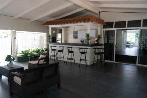 un soggiorno con cucina e un bar con sgabelli di Villa Grand Jardin a Jan Thiel