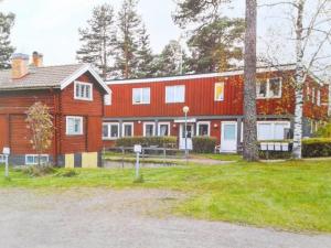 a large red house with a tree in front of it at Hostel Gästhem Glassen Apartment in Rättvik