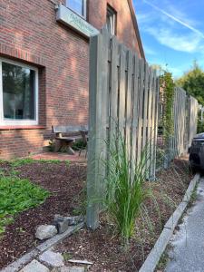 a fence in front of a brick building with a bench at Deich Winde 9.2 in Dorum Neufeld