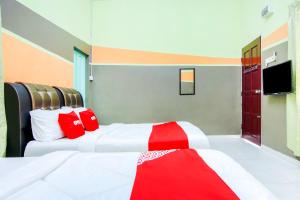 Cette chambre d'hôtel comprend 2 lits avec des oreillers rouges. dans l'établissement Tangkak Mawadahh Inn Stay, à Tangkak