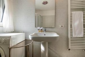 La salle de bains blanche est pourvue d'un lavabo et d'un miroir. dans l'établissement Appartamenti Montefelice, à Bardolino