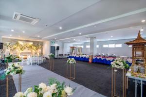 a banquet hall with tables and chairs and flowers at Cleo Hotel Jemursari Surabaya in Surabaya