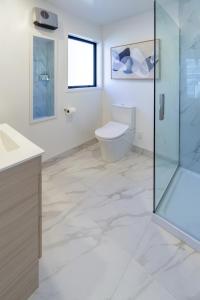 a bathroom with a toilet and a glass shower at Walk to Riverside Market 4 bed 4 bath with car park in Christchurch