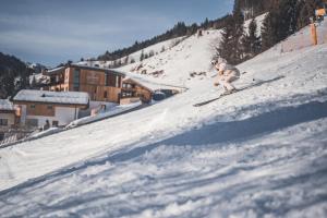 a person is skiing down a snow covered slope at Landhaus Saalbach - Ski in & out in Saalbach Hinterglemm