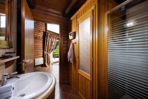 a bathroom with a white sink and a wooden door at Natura Chalets in Méga Khoríon