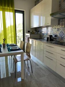 a kitchen with white cabinets and a table and chairs at La Peonia in Castellammare di Stabia