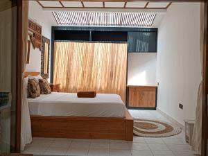 a bedroom with a bed and a large window at Katang - Katang Guest House in Denpasar