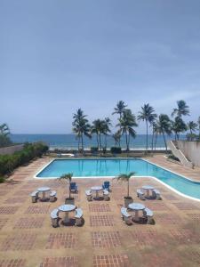 a swimming pool with chairs and umbrellas next to the ocean at Esparta Suite isla de margarita in Porlamar