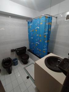 a bathroom with a sink and a toilet and a shower curtain at Esparta Suite isla de margarita in Porlamar