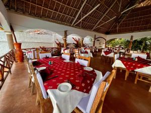 a restaurant with tables and chairs with red table cloth at Zanzibar Bahari Villas in Matemwe