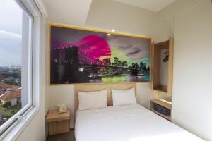 a bedroom with a bed and a large window at Cleo Hotel Jemursari Surabaya in Surabaya
