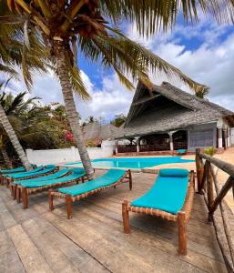 a row of chaise lounge chairs next to a swimming pool at Zanzibar Bahari Villas in Matemwe