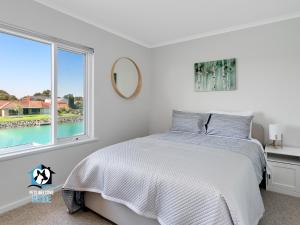 a white bedroom with a bed and a window at Beautiful Lake Views with Pontoon in Encounter Bay