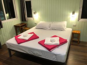 a bed with red and white towels on it at Rabbit House แรบบิท เฮ้าส์ in Ban Han Tra Fang Nua