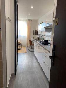 a kitchen with white cabinets and a dining room at Le Refuge du Bord de Mer 2 pers- Studio avec parking à 500m de la mer in Houlgate